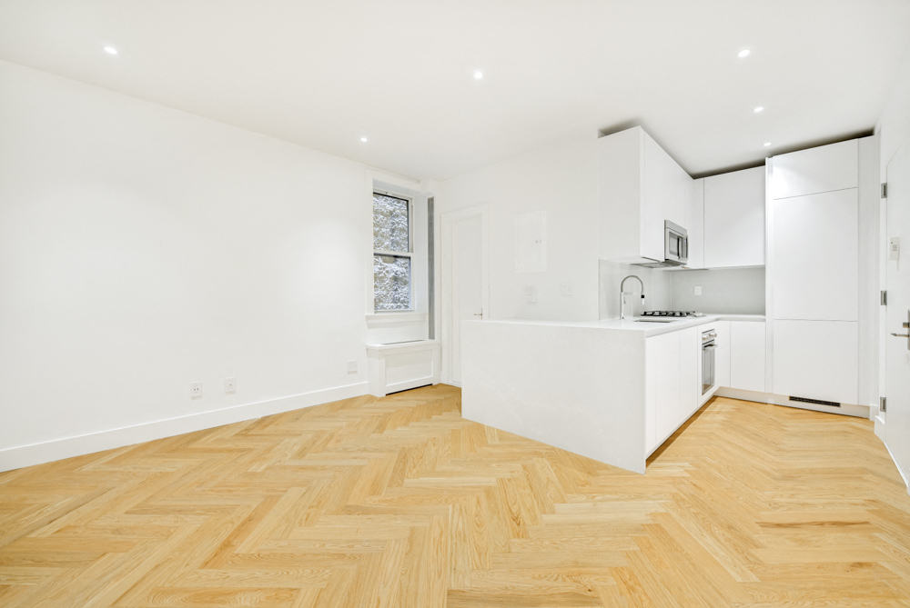 A kitchen with white cabinets and a wooden floor.