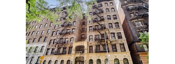 A row of brown buildings with fire escapes on the side.