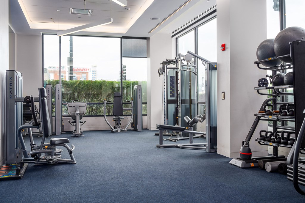 a fitness room with weights and cardio equipment and glass windows