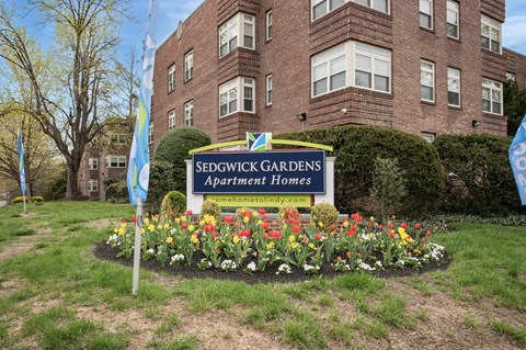 A sign for Sedgwick Gardens Apartments is in front of a brick building.