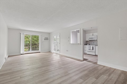 A spacious room with wooden flooring and white walls.