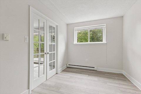 A room with a window and a door leading to a balcony.
