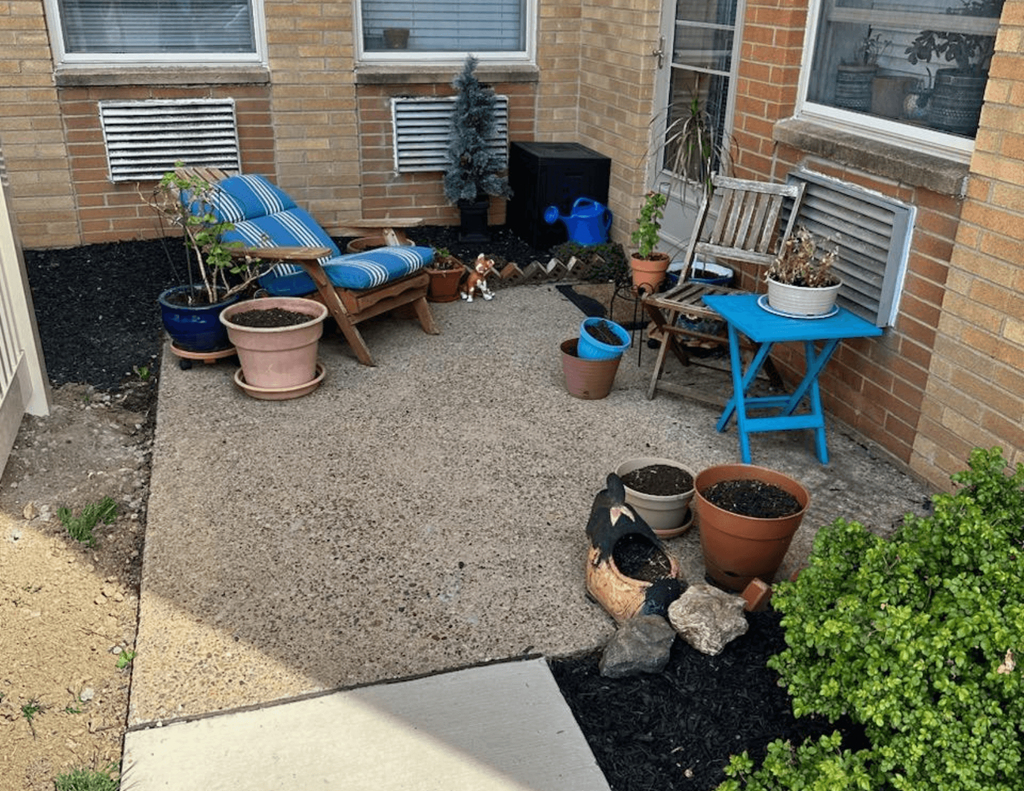 a patio with a blue table and two chairs in front of a brick building