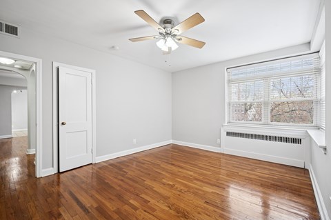A room with a ceiling fan and wooden floors.