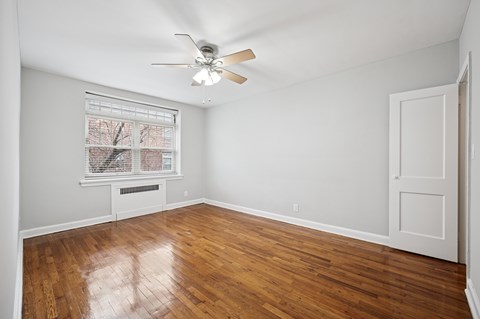 A room with a ceiling fan and a window with blinds.