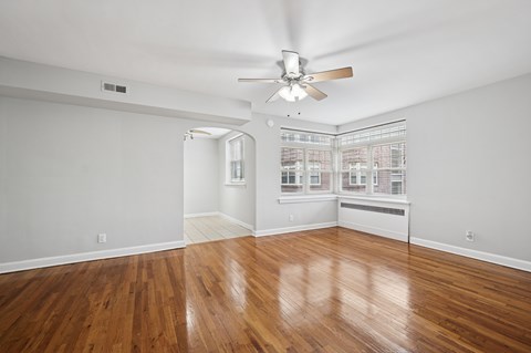 A room with a ceiling fan and wooden flooring.