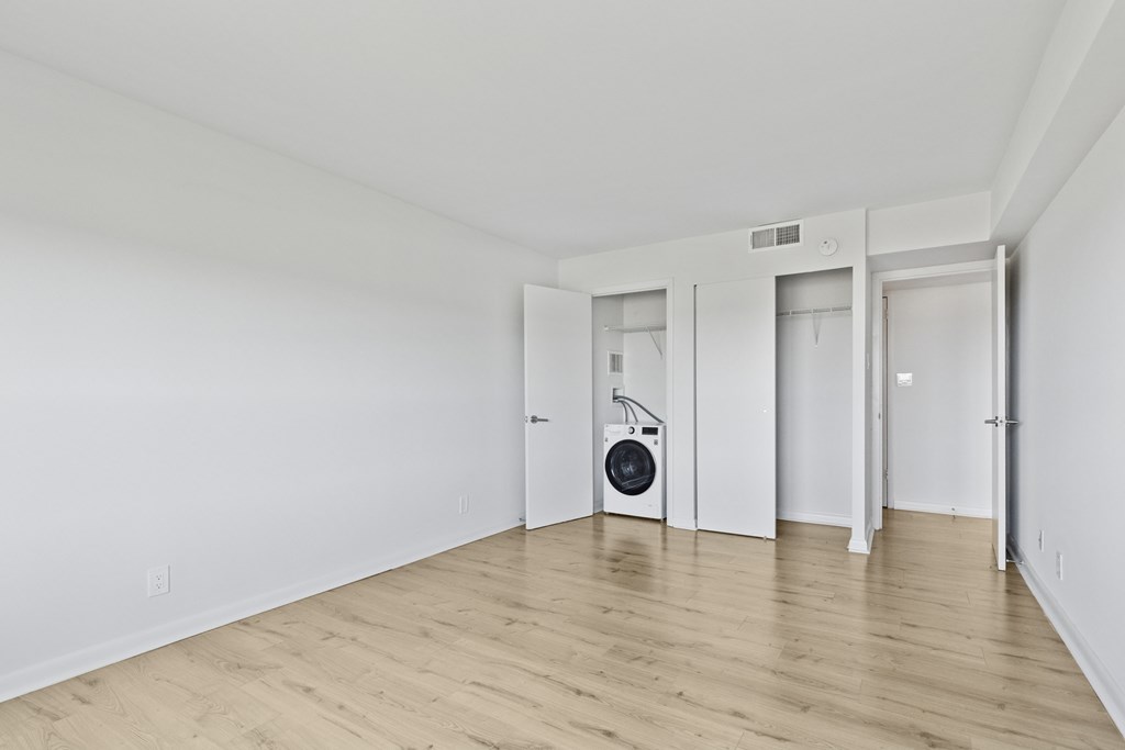 A room with a wood floor and a wall-mounted heater.