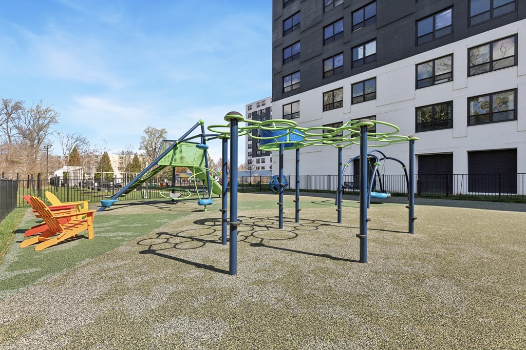 A playground with a green and blue slide and a yellow bench.