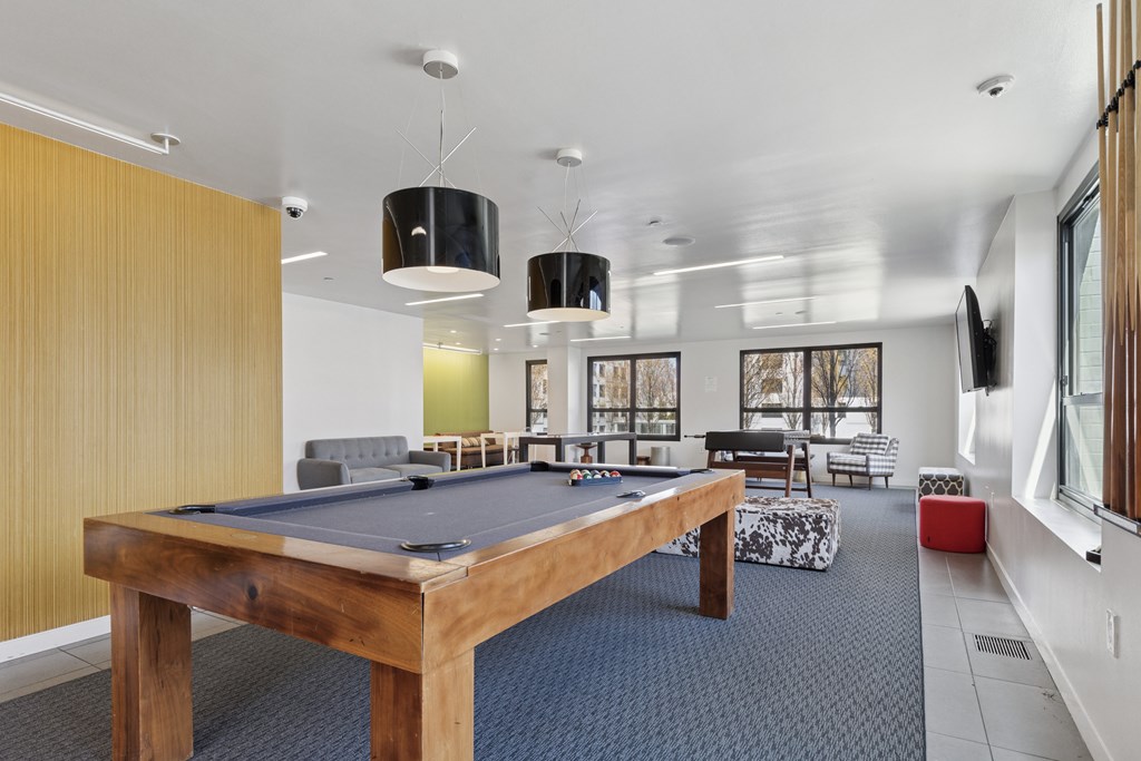 A pool table is in the middle of a room with a couch and chairs.