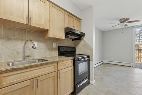 A kitchen with wooden cabinets and a black oven.