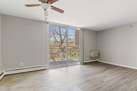 A room with a ceiling fan and sliding glass doors leading to a balcony.
