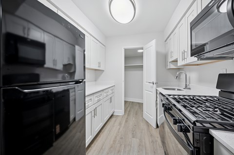 A modern kitchen with black appliances and white cabinets.