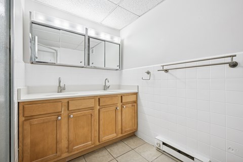 A bathroom with a white tiled wall and a wooden vanity.