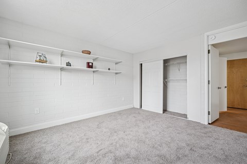 A white room with a carpeted floor and a white wall with a door.