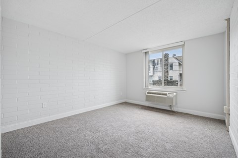 A room with a window and a carpeted floor.