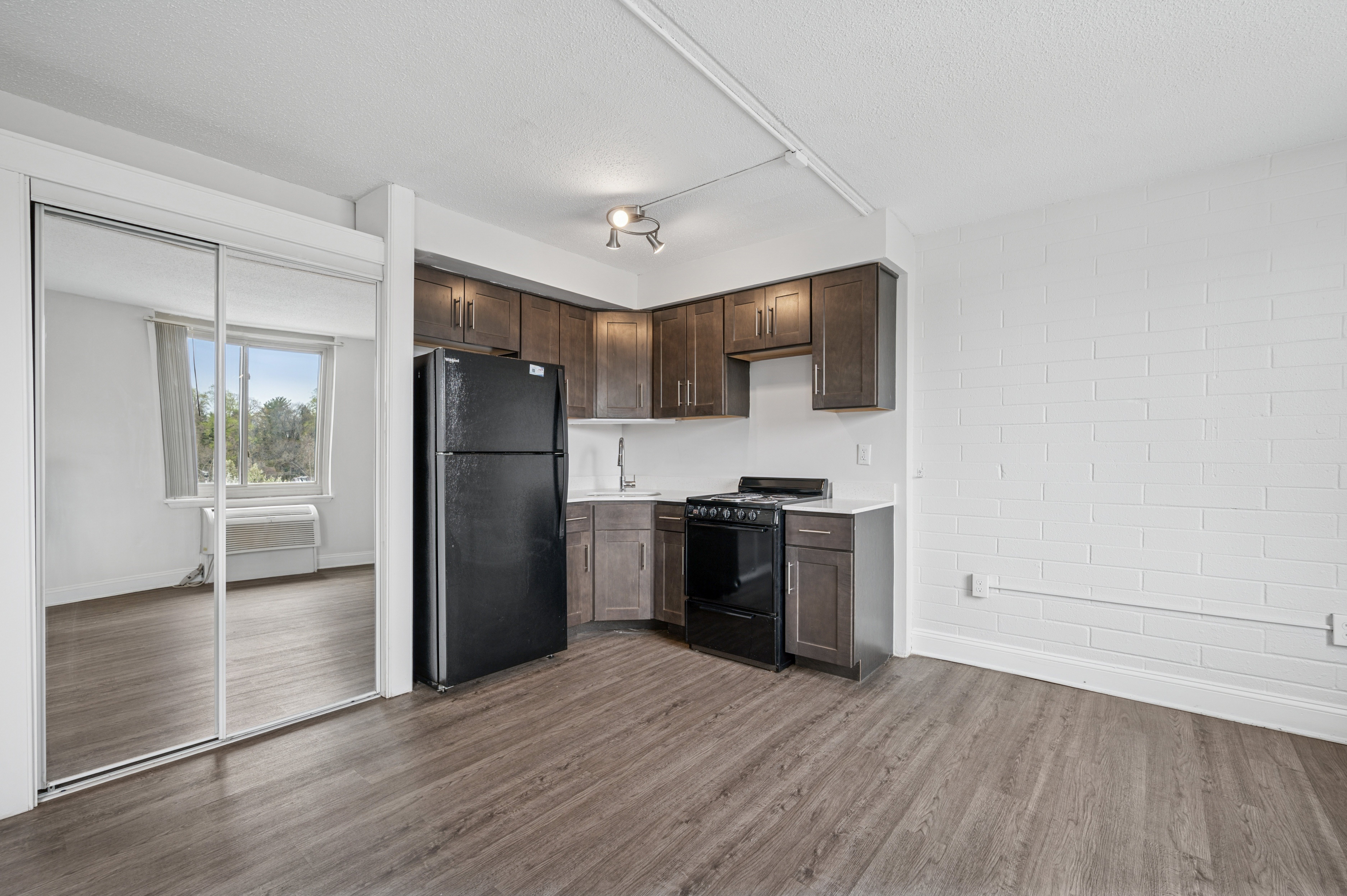 A kitchen with a black refrigerator and wooden cabinets.