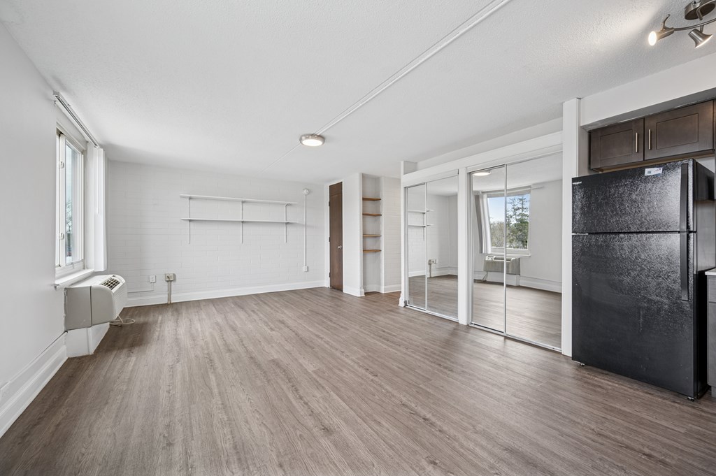 A spacious kitchen with a black fridge and wooden flooring.