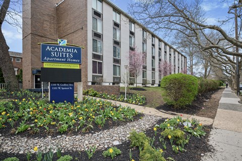 A sign for Academia Suites Apartments Homes is in front of a building.