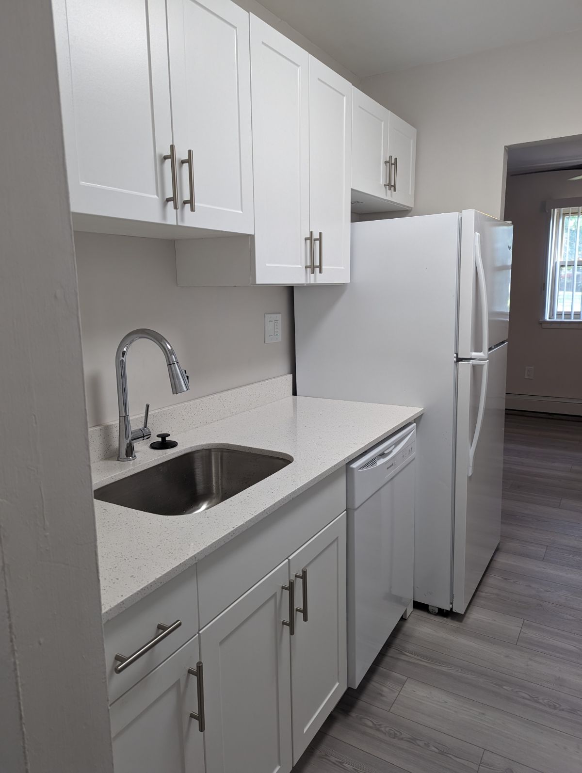 A kitchen with white cabinets and a white refrigerator.