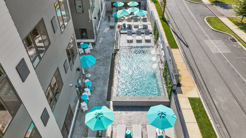 A pool surrounded by a concrete wall and blue umbrellas.