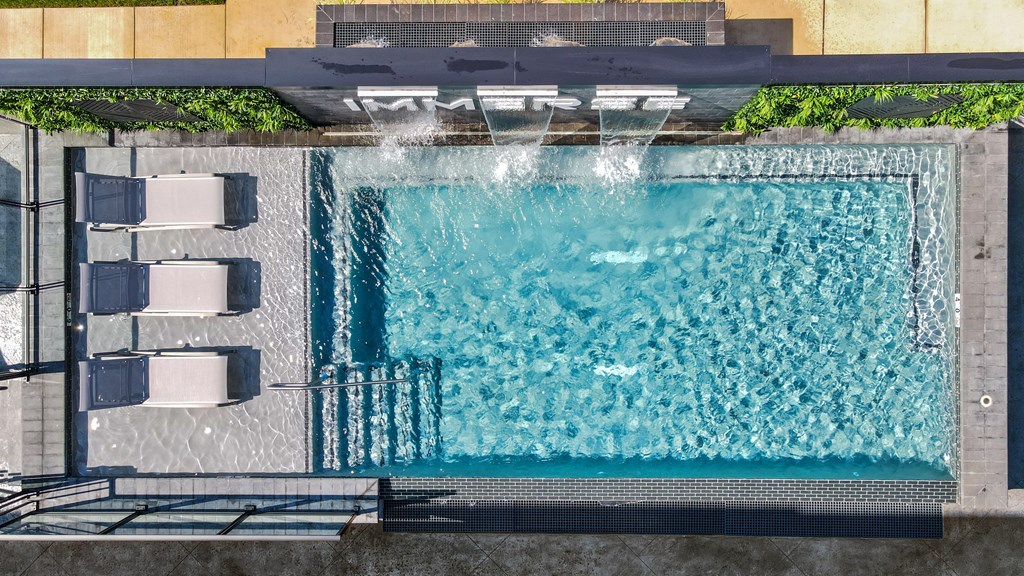 A pool with a waterfall feature and lounge chairs.