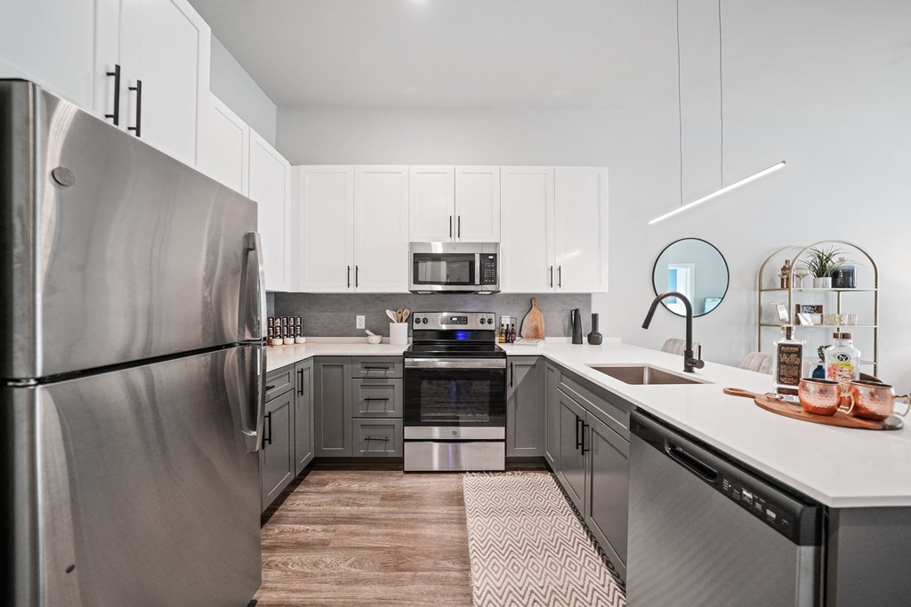 A modern kitchen with a stainless steel refrigerator and wooden flooring.