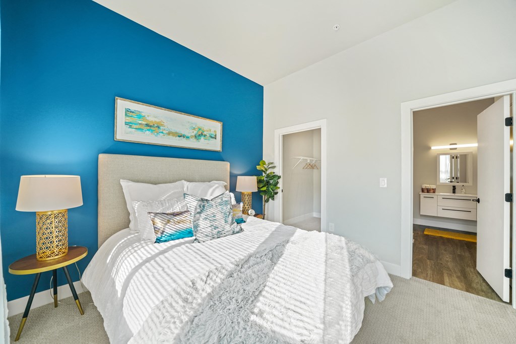 A bedroom with a white bed and a painting on the wall.