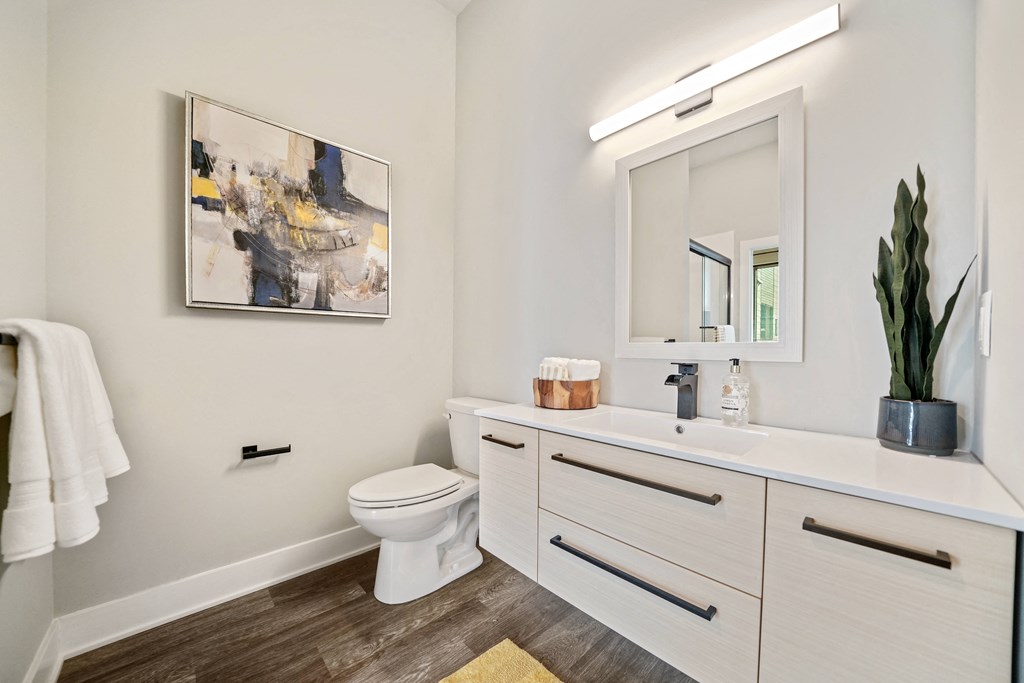 A bathroom with a toilet, sink, and a painting on the wall.