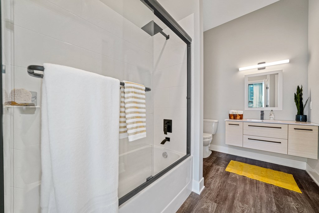 A bathroom with a walk-in shower and a yellow rug on the floor.