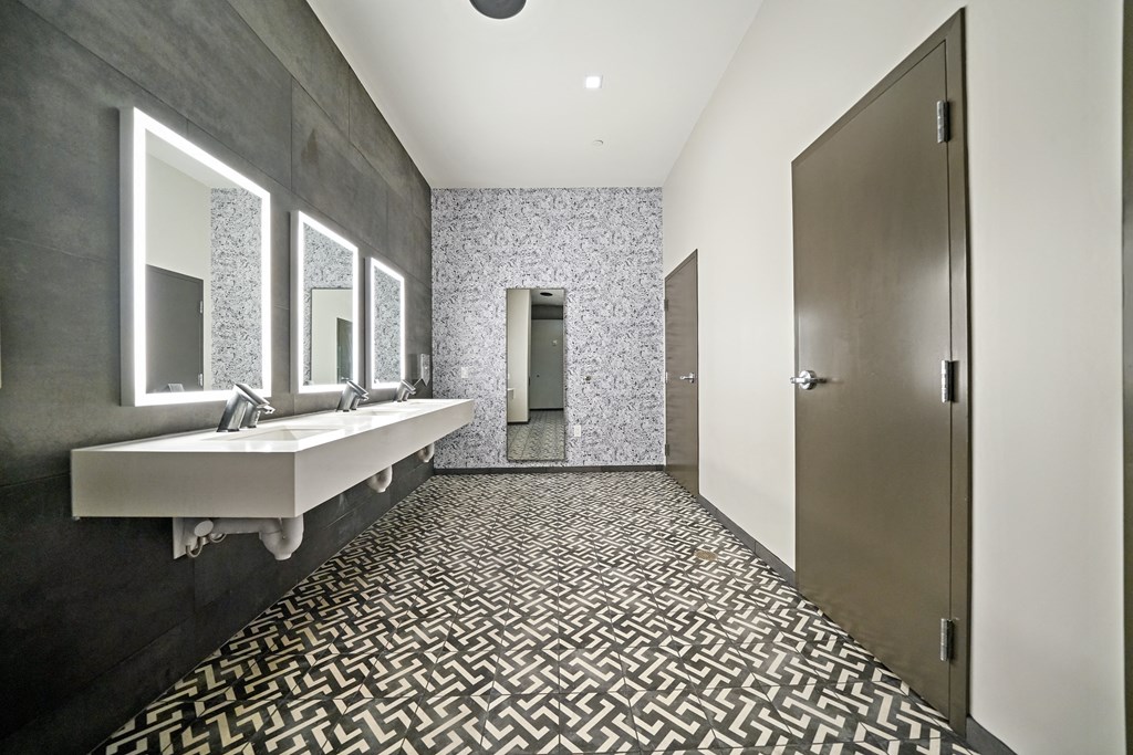 A bathroom with a sink, mirrors, and a tiled floor.