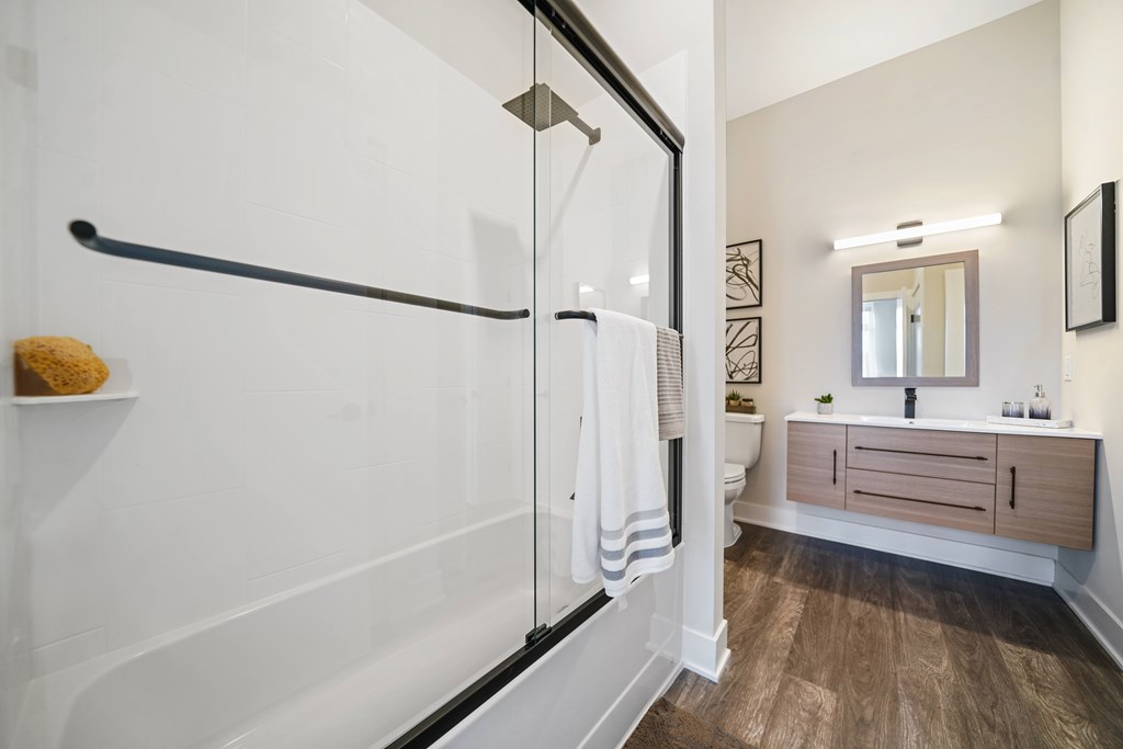 A bathroom with a white tub and wooden floors.