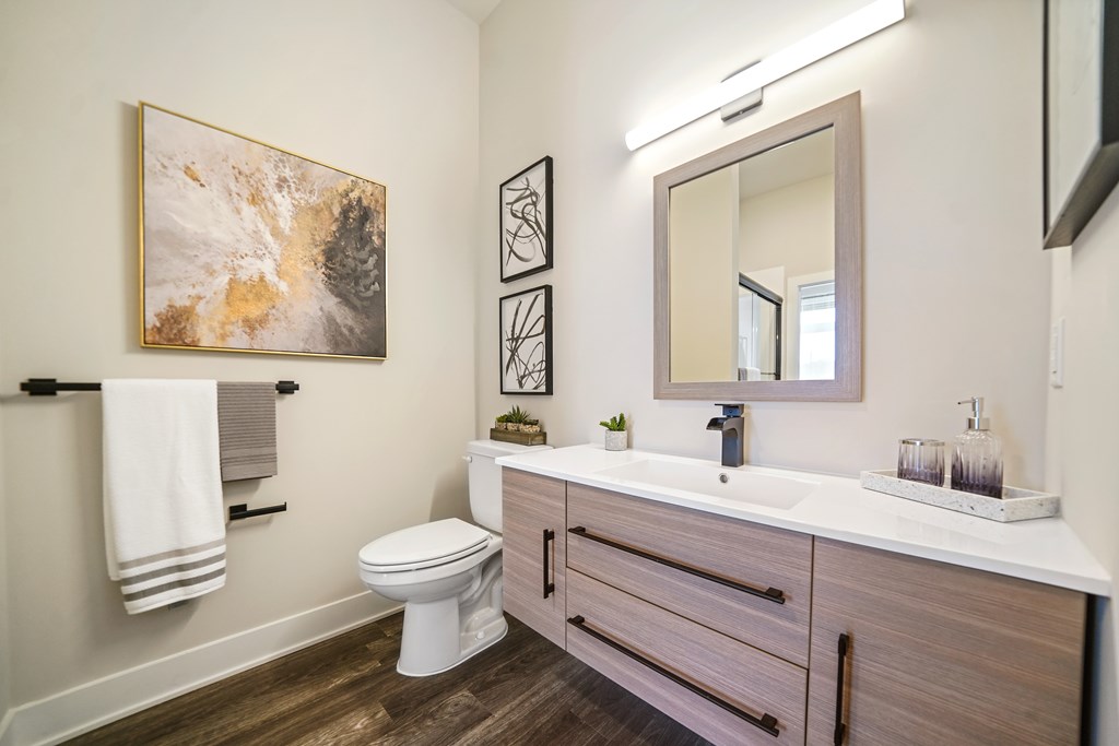 A bathroom with a toilet, sink, and a painting on the wall.