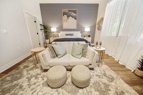 A bedroom with a bed, two lamps, a painting, and a white couch.