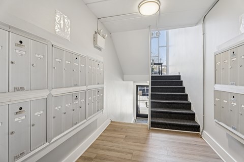 A hallway with a staircase and lockers on both sides.
