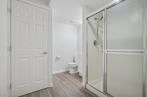 A white door is on the left and a glass shower door is on the right.