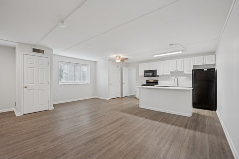 A spacious room with wooden flooring and white walls.