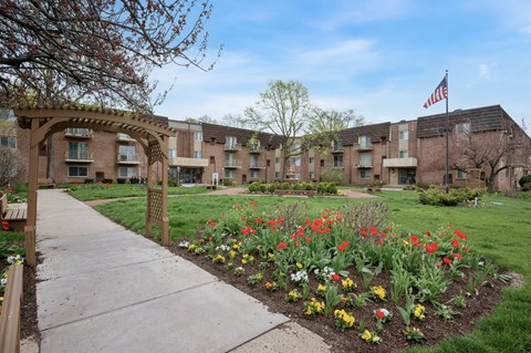 A garden with a variety of flowers in the foreground and apartment buildings in the background.