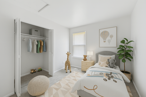 A bedroom with a bed, a giraffe toy, a potted plant, and a wardrobe.