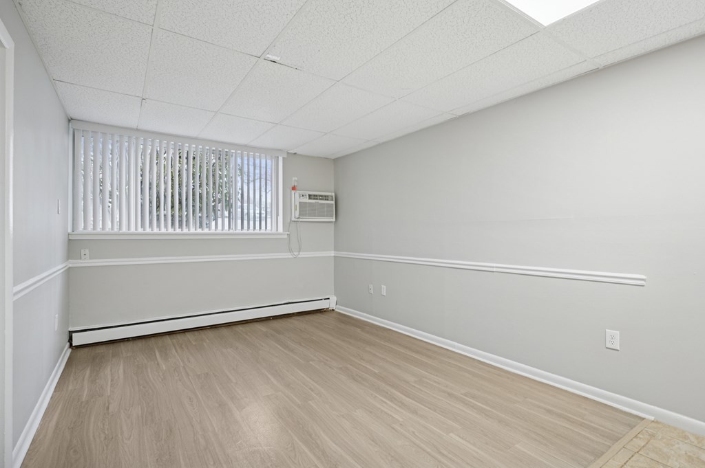 A room with a window covered by blinds and a wooden floor.