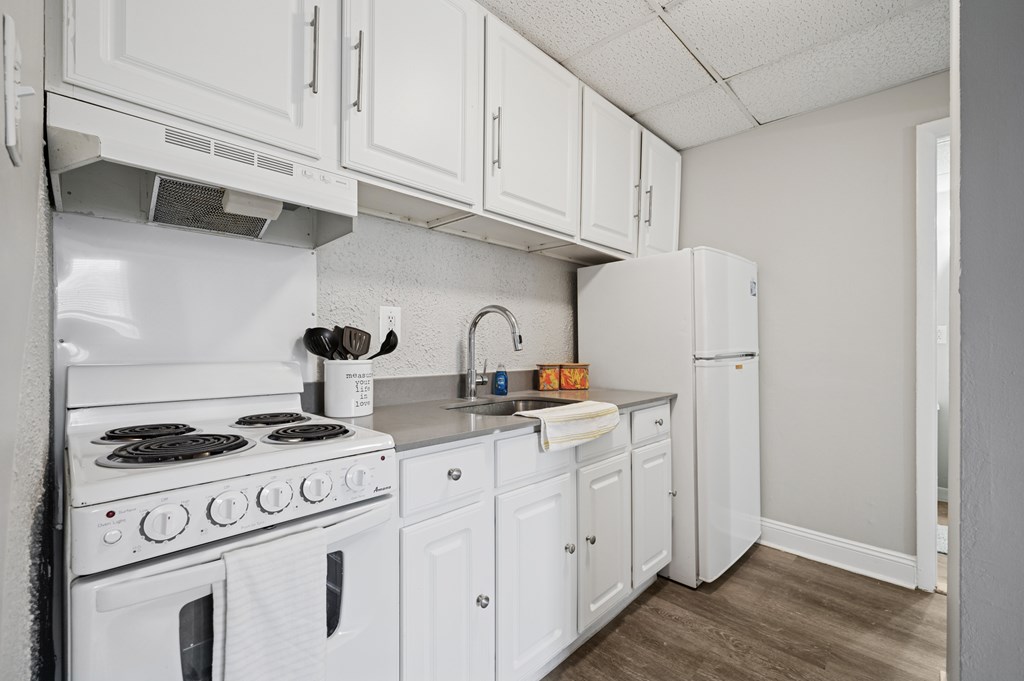 A white kitchen with a stove, oven, and refrigerator.
