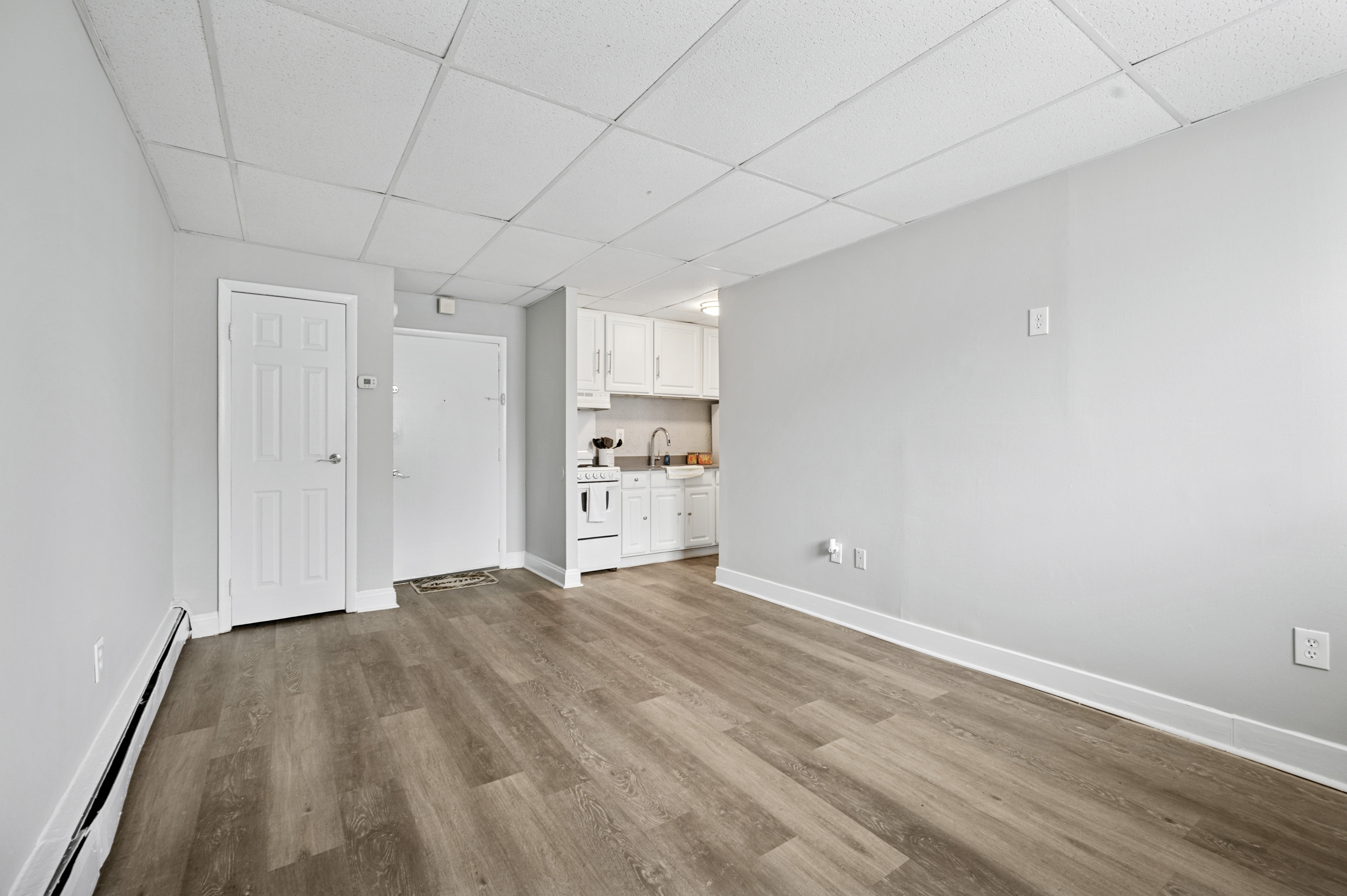 A room with a white door and a kitchenette.