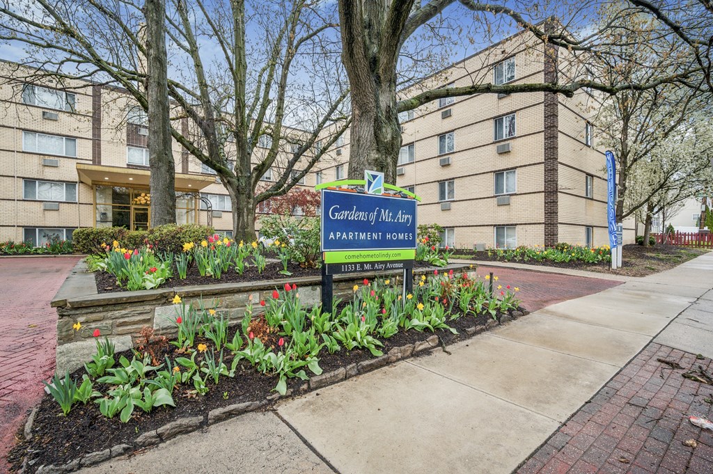A sign for Garden Mt. Airy Apartment Homes stands in front of a building.