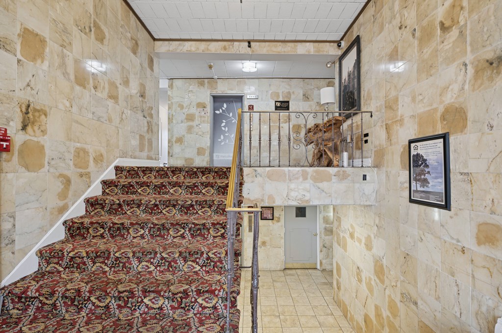 A staircase with a carpeted runner and stone walls.