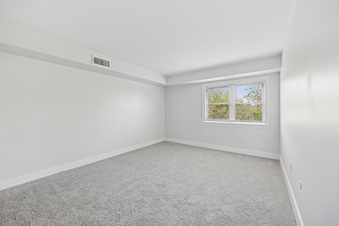 A room with a window and carpeted floor.