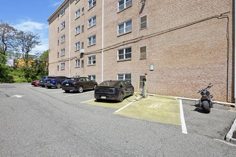 A parking lot with cars and a motorcycle in front of a brick building.