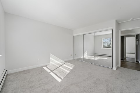 A room with a carpeted floor and a glass door leading to another room.