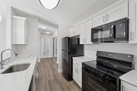 A black refrigerator and oven in a kitchen with white cabinets.