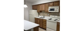 A kitchen with white appliances and wooden cabinets.