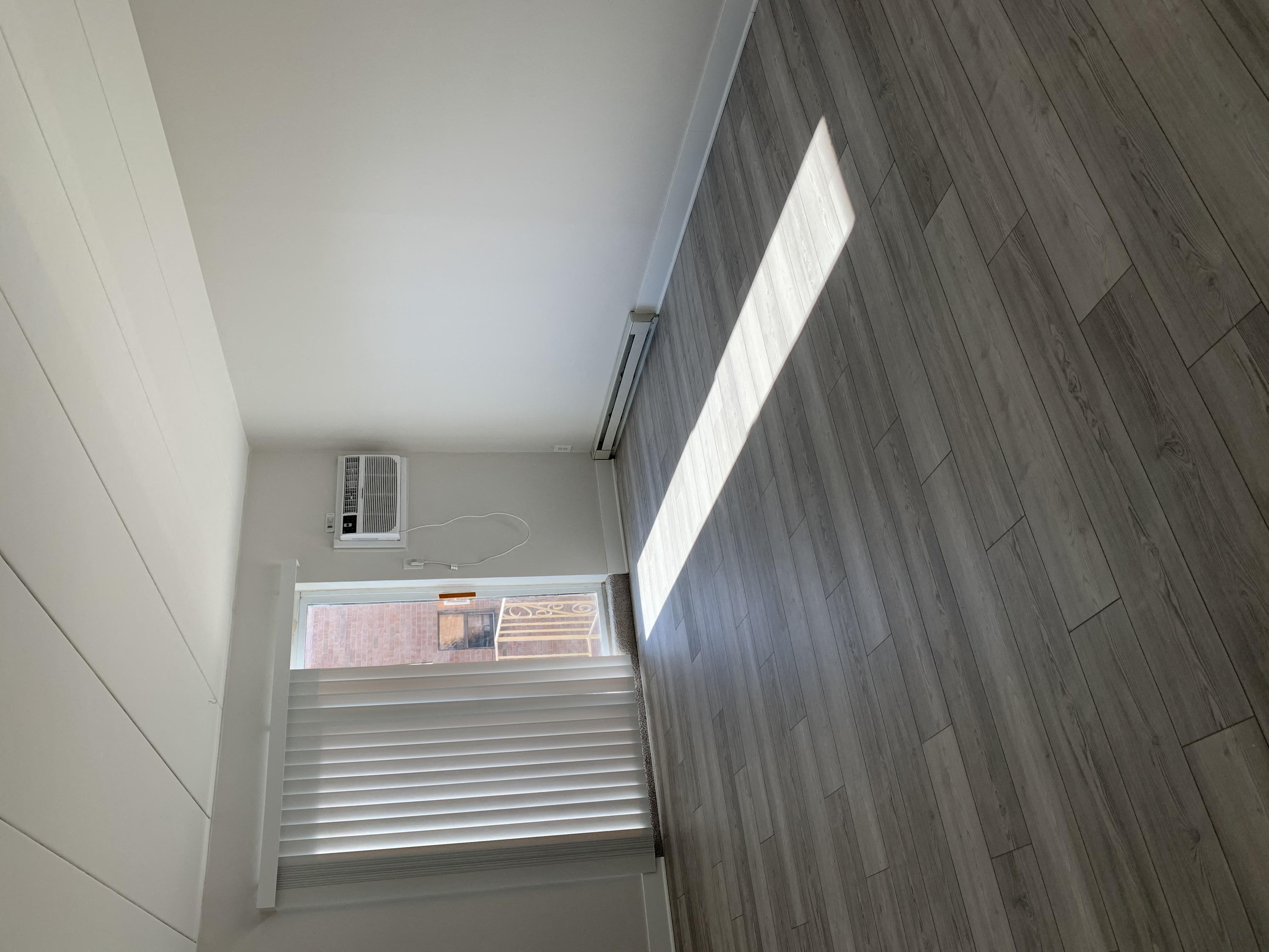 an air conditioning unit sits on a wooden floor in a room with white walls and wood floors
