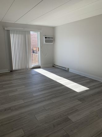 an air conditioning unit sits on a wooden floor in a room with white walls and wood floors